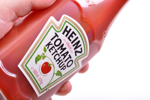 Heinz Tomato Ketchup bottle in a hand, on a white background