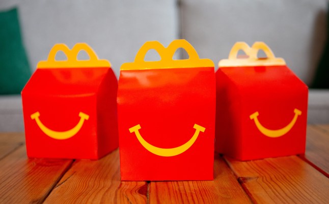 Three McDonald's Happy Meal boxes on a table in a living room, with a grey sofa behind them