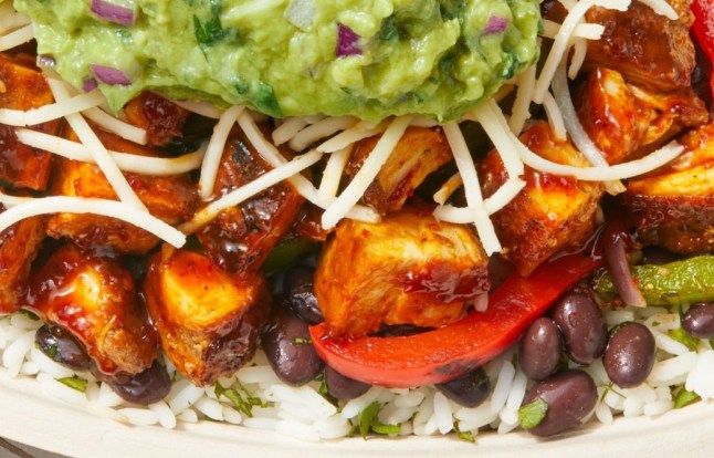 The new honey chicken in a burrito bowl from Chipotle. The bowl contains rice, beans, peppers, honey chicken, cheese and guacamole.
