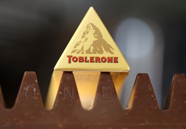 A close up of a Toblerone bar with the end of the packaging showing the old design of the Matterhorn mountain resting above it.