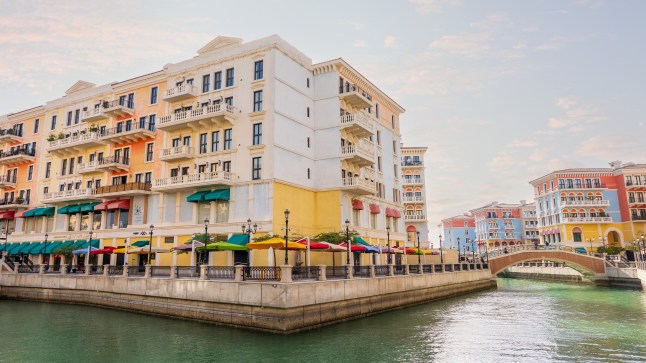 A corner view of a street on a canal in the Qanat Quartier of Pearl Island in Doha, Qatar. The buildings are pastel coloured.