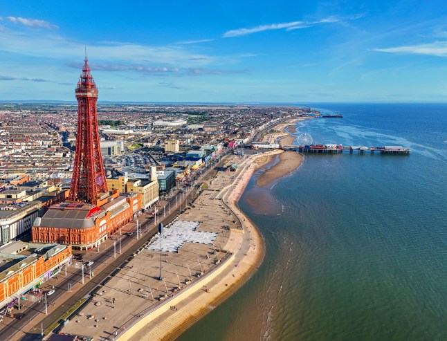 An aerial view of Blackpool's seafront, with a red tower, beach and pier.