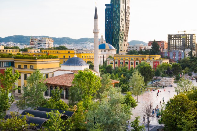 Skanderbeg Square in Tirana, Albania, with Et'hem Bey Mosque in the foreground and the green and blue skyscraper 4 Ever Green Tower in the background.