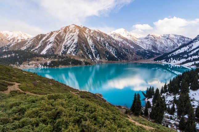 A scenic view of Kazakhstan's Big Almaty Lake with the Tianshan Mountains in the background.