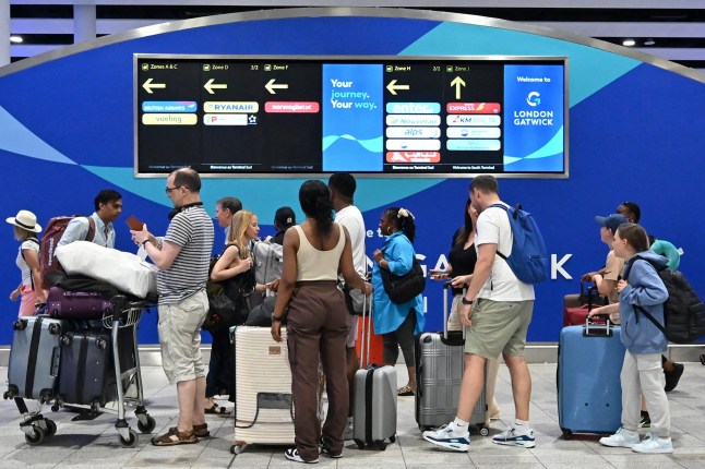 Passengers wait in the check-in area of Gatwick Airport as some flights are cancelled or delayed.