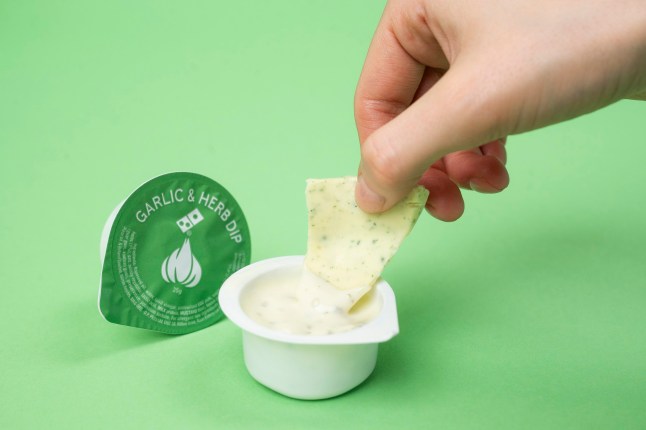 A hand dipping the Garlic & Herb Easter Egg inside the signature sauce.