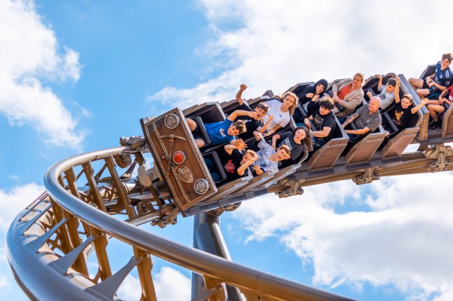 People riding a rollercoaster at Drayton Manor theme park, as it turns around a curved part of the track.