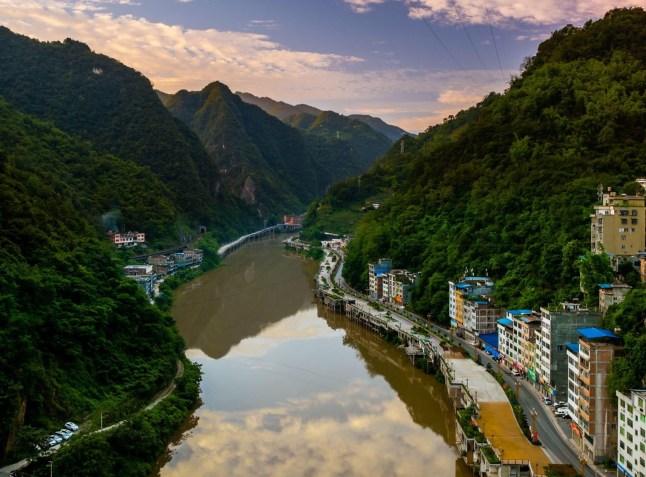 A narrow town called Yanjin in China, stretching along the Guanhe River between tall mountains on either side.