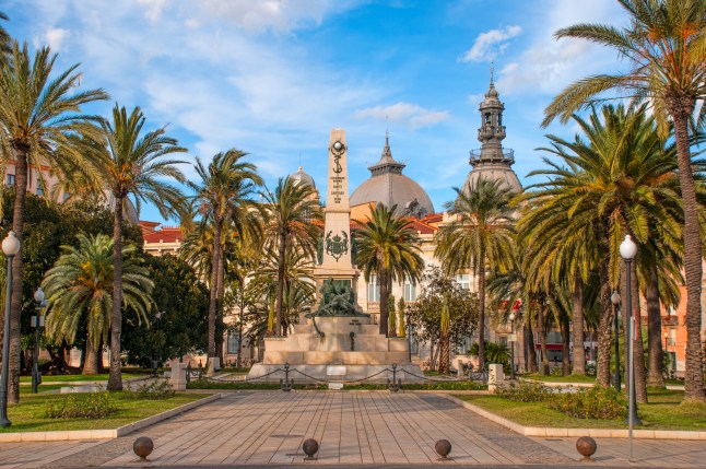 A garden and historic building on a sunny day in Murcia, Spain