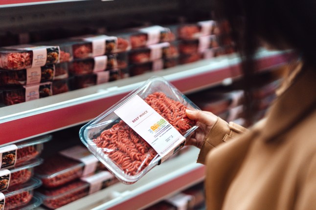 Woman shopping in supermarket holding a packet of beef mince