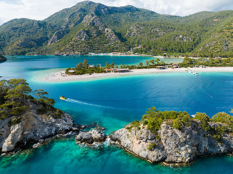 An aerial view of Ölüdeniz Beach in Fethiye, Turkey. The water is turquoise and crystal clear, and trees pepper the rocks.