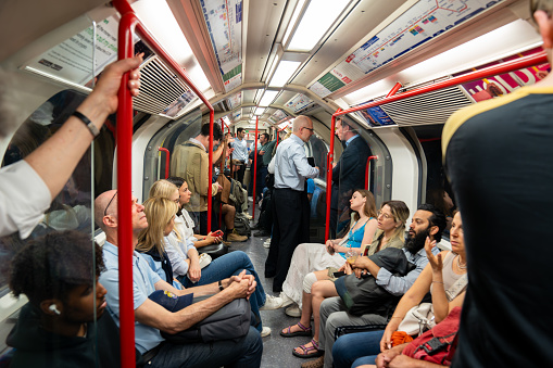 People sitting and standing on a crowded Central Line Tube train in London.