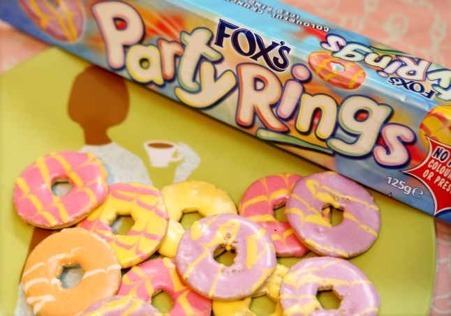 A packet of Fox's Party Rings biscuits and some of the colourful biscuits on a table