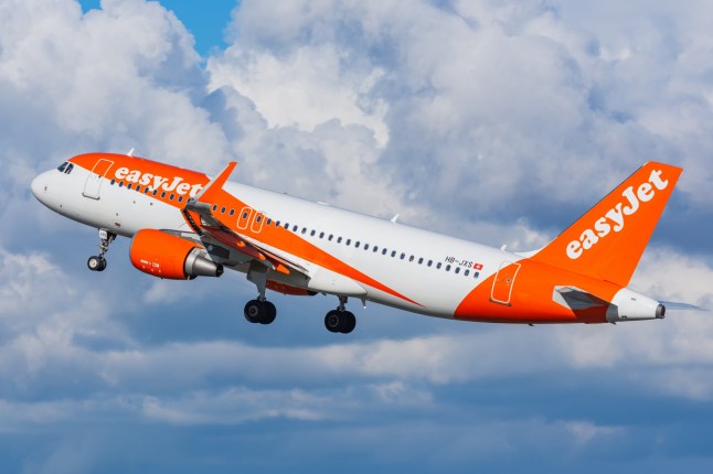 An EasyJet flight takes off against a blue sky.