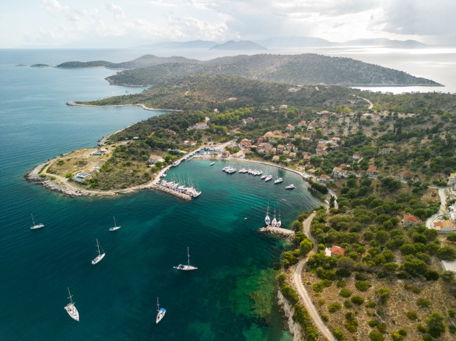 Beautiful coast with marina and small village on Mediterranean sea and anchored sailboats and catamarans. Island of Kastos, Greece.