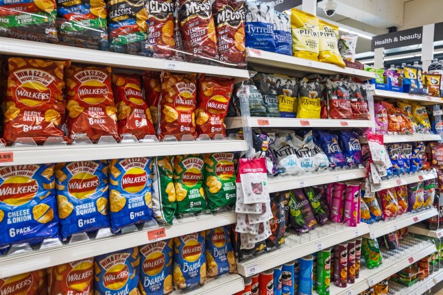 Supermarket shelves stocked with a wide variety of crisps and snack bags, including Kettle Chips